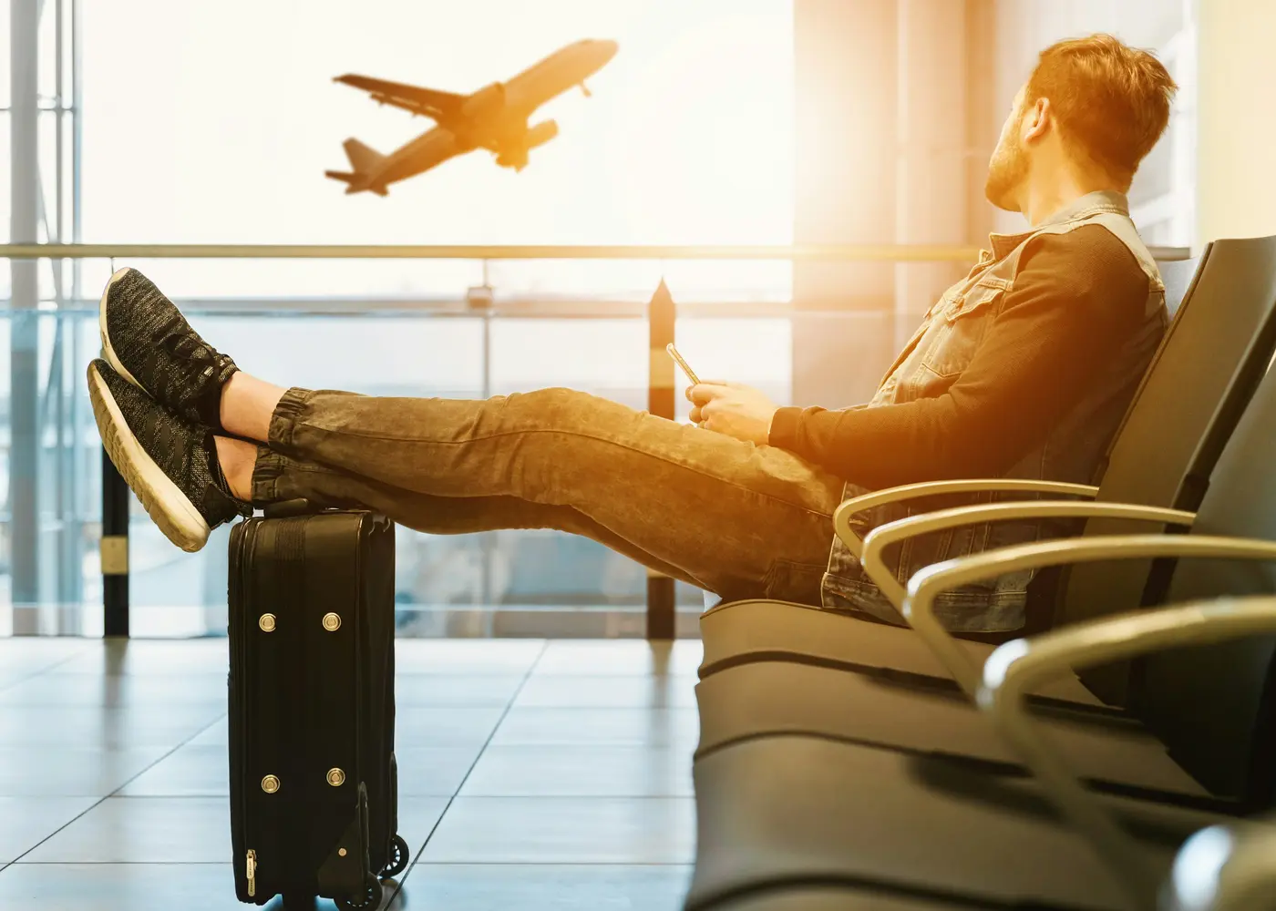Viajante descansando em uma sala de embarque com um avião ao fundo