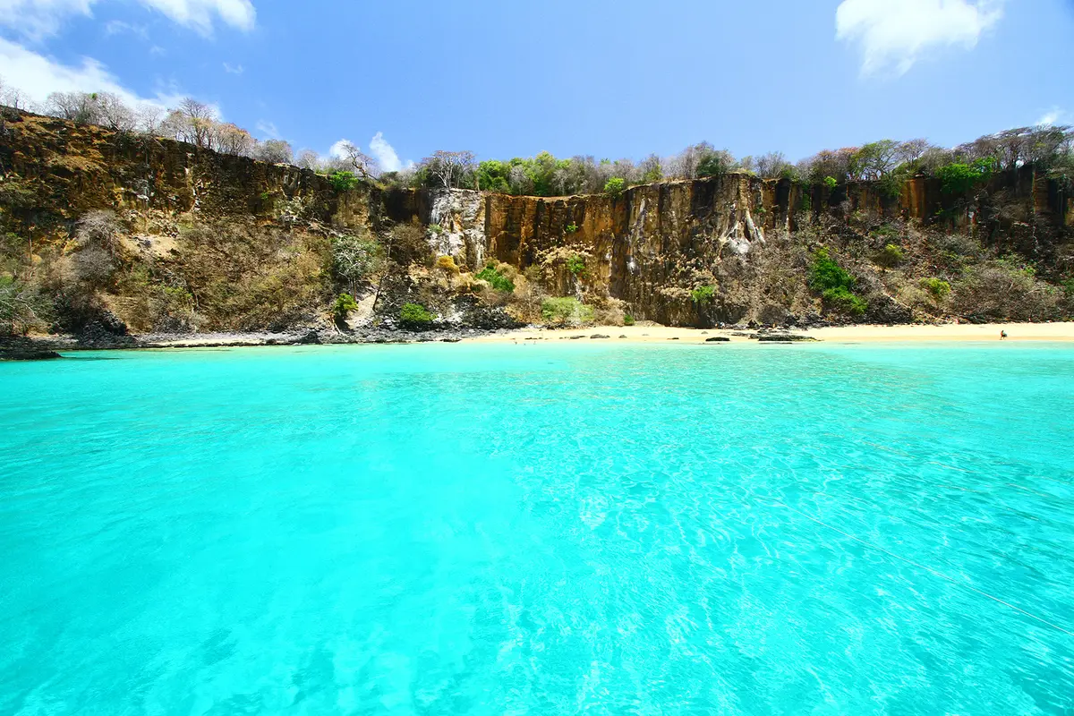 Costa de Noronha com falésias e mar transparente