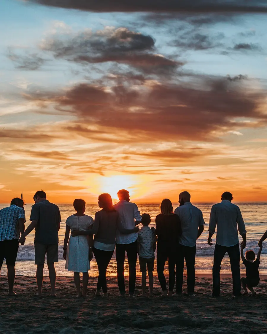 Família caminhando na praia ao pôr do sol